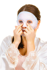 Woman applying sheet mask on face
