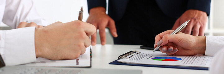 Group of people hold silver pen ready to make note