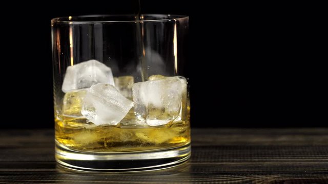 whiskey is poured into a glass with ice