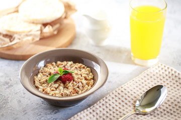 Baked granola with milk and raspberries in a plate, whole grain breads and freshly squeezed juice. Healthy breakfast. Delicious muesli.