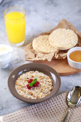 A healthy and dietary breakfast. Baked granola with milk and raspberries in a plate, whole grain breads and freshly squeezed juice. Delicious muesli.