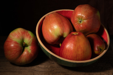 Apples and pear in a plate on old wood