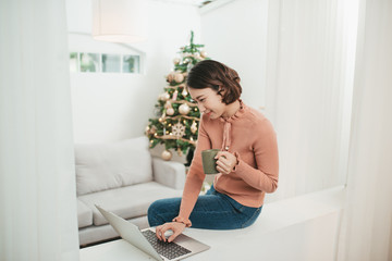 Happy young woman browsing the internet over the christmas holiday season