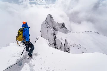 Foto op Canvas An alpinist climbing an alpine ridge in winter extreme conditions. Adventure ascent of alpine peak in snow and on rocks. Climber ascent to the summit. Winter ice and snow climbing in mountains. © Ondra