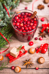 Glass of cranberry drink, cranberries, cinnamon sticks, anise stars on a wooden background. Christmas winter drinks.
