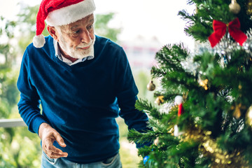 Senior man relaxing  decorating christmas tree and smiling while celebrating new year eve and enjoying spending time together in christmas time at home