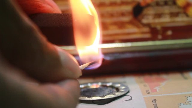 Close up shot of man lighting up dhoop batti / incense stick and it is burning with some smoke on the pooja room