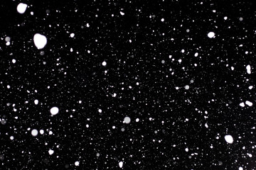 Winter snow storm with real snowflakes on a dark black sky. Many snowflakes to be used on overlay