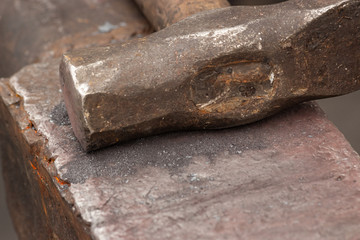 Old rusty hammer lies on the anvil. Blacksmith, metalsmith, farrier tools. Close view.