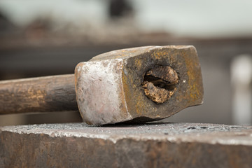 Old rusty hammer lies on the anvil. Blacksmith, metalsmith, farrier tools. Close view.