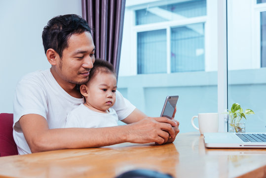 Man father working on laptop computer and using smartphone technology