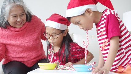 Grandmother and little grandchildren playing with candy cane