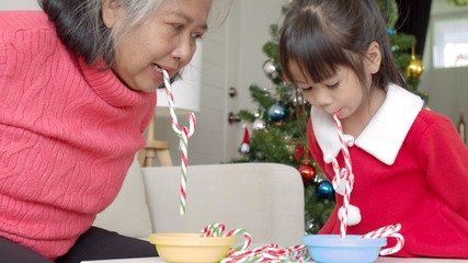 Grandmother and little granddaughter playing with candy cane