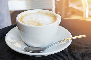 Cup of fresh Italian cappucino on the table in street caffe