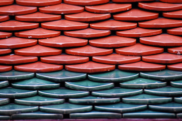 Abstract scene of Red and green  earthenware tiles or calls tiles consists of fish scales on the roof of temple bangkok thailand