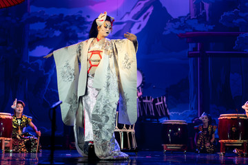 Traditional Japanese performance. Actress in traditional white kimono with long sleeves and fox mark dancing.