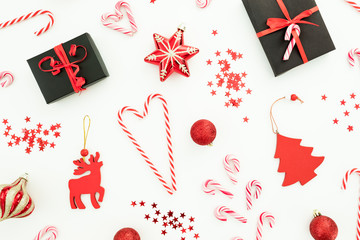 Christmas composition. Gift box, red decoration, candy canes and confetti on white . Flat lay