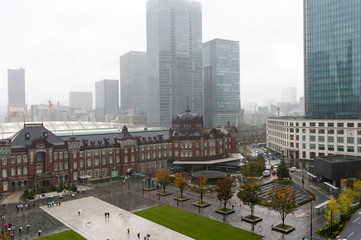 雨の日の東京都千代田区丸の内の東京駅と高層ビル群
