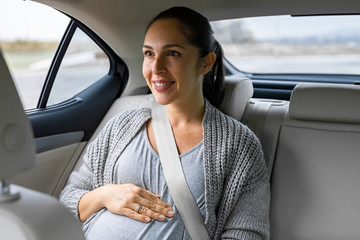 Pregnant Young Woman is driving in the Car