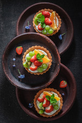 Freshly baked mini tart with strawberries, orange, kiwi and grapes