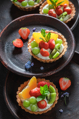Tasty mini tart with fresh fruits, mint and whipped cream