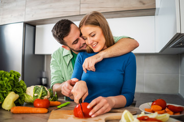 Young couple is preparing meal in their kitchen.