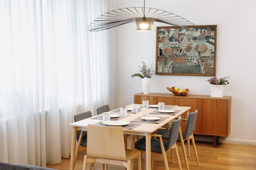 Interior of a dining room with large window and a painting on the wall