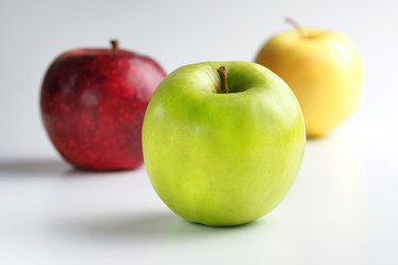Apples green, yellow and red on a white background.