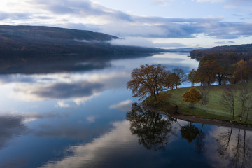 Breathtaking vibrant aerial drone landscape images over Coniston Water at sunrise on beautiful Autumn Fall morning