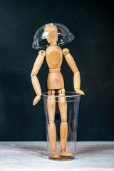 Fototapeta na wymiar wooden man sits in a plastic glass