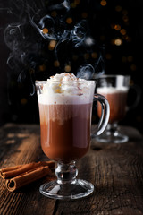 Cup of hot chocolate with cinnamon decoration on wooden table background