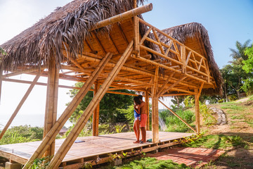 Couple in wooden bamboo hut. Romantic honeymoon. Meditating and looking at beautiful sunset over Montanita beach town. Shot in yoga retreat in Ecuador.