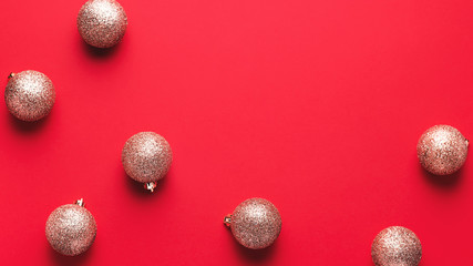 Shiny golden christmas baubles in chaotic order on red background, copy space, minimal flat lay, top view