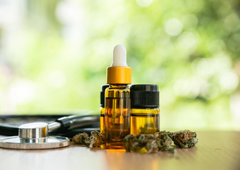 Obraz na płótnie Canvas Marijuana plant with buds and essential oil on a wooden table, Marijuana herbal cancer treatment concept.