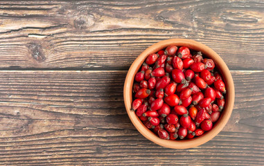 Clay bowl with rosehip fruits, rich in vitamin C, immunity protection and antioxidant. Top view, copy space
