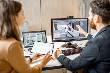 Two creative office employees making interior design on the computer and digital tablet at the...