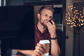 Smiling worker sitting at table with mobile phone