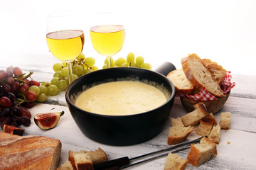 Gourmet Swiss fondue dinner on a winter evening with assorted cheeses on a board alongside a heated pot of cheese fondue with two forks dipping