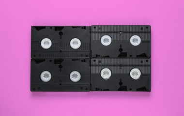 Retro video cassettes on pink background. Top view