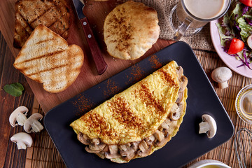 Mushroom omelette in black plate on wood table