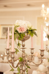 silberner Kerzenständer mit rosa Kerzen und frischen Blumen