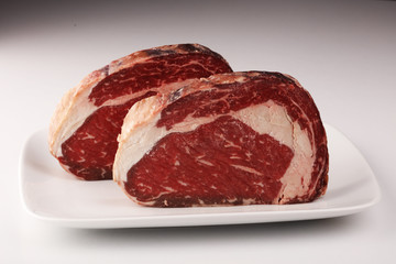 Raw fresh meat Ribeye Steak, seasoning and meat fork on rustic background