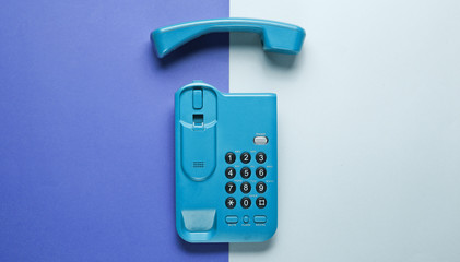 Wireless office phone with handset on purple gray background. Top view.