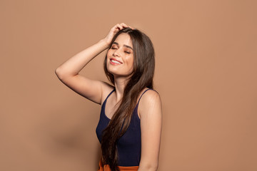 Freestyle. Young girl in top standing studio isolated on brown posing to camera closed eyes cheerful
