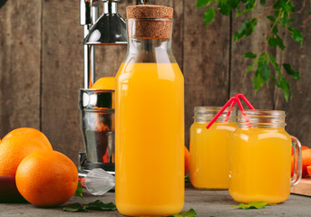 Bottle of orange juice with oranges on wooden table
