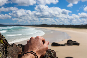 Man's hand with a long and empty beach in the background