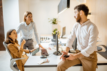 Fototapeta premium Creative office employees working on some architectural project, talking at the working place of the modern office studio. Concept of an architectural business and creative work