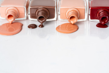 Nude colors nail polish spilled over white background