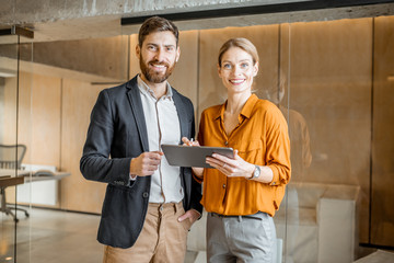 Portrait of a two colleagues standing together with digital tablet in creative studio. Work in...