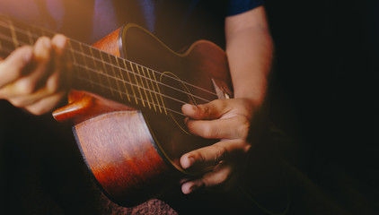 Hands playing acoustic ukulele guitar.Music skills show - obrazy, fototapety, plakaty